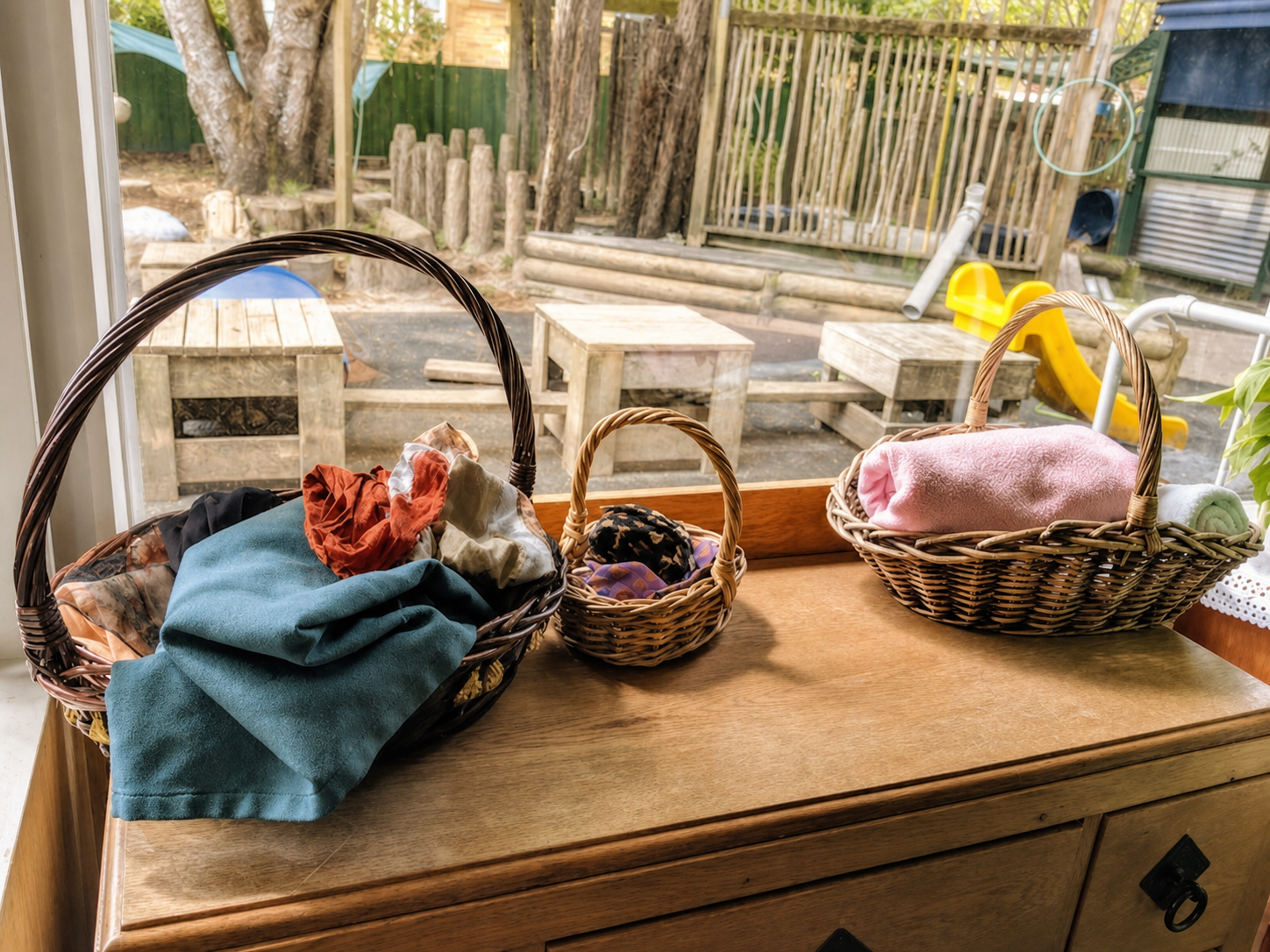 Baskets of open-ended materials beside the outdoor play space