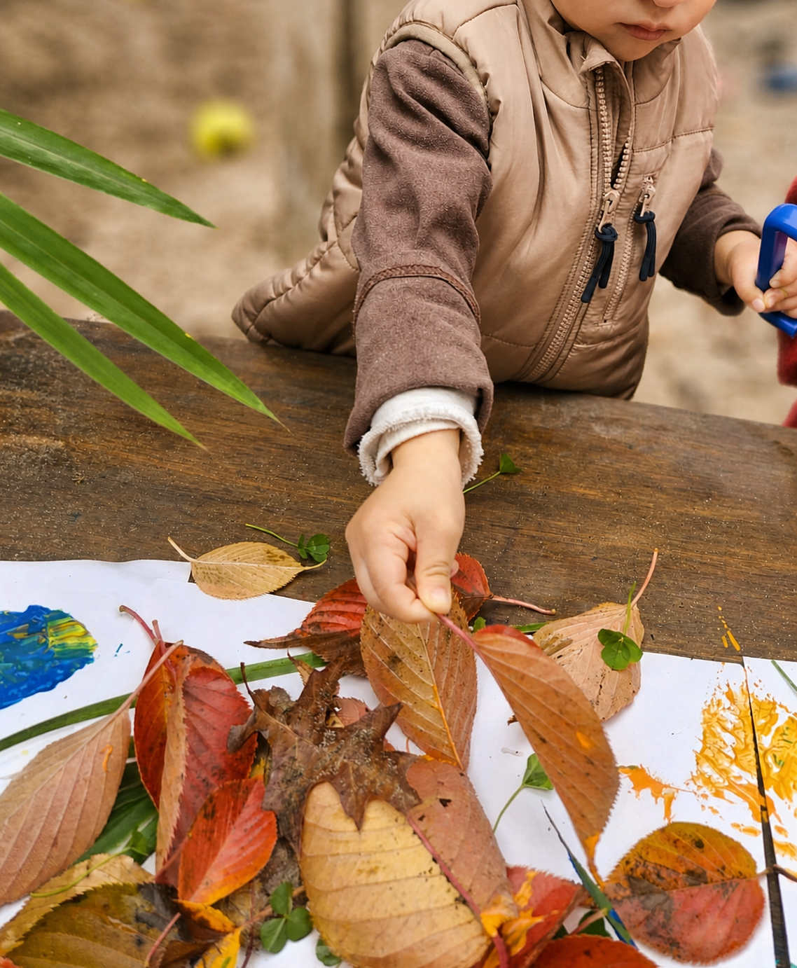 Child making art with autumn leaves at Royal Oak