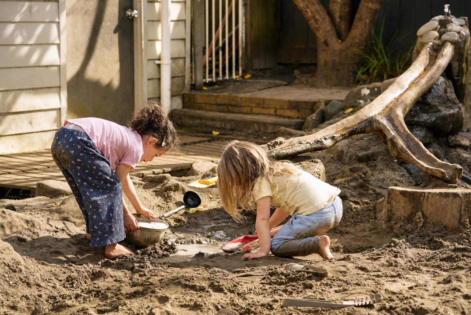 Two children exploring natural logs and materials outdoors